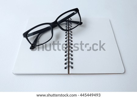 White office desk table with eye glasses, notebook . Top view with copy space, flat lay.