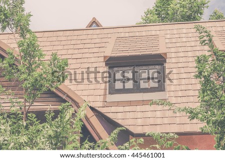 Brown tile window and house roof in garden against blue sky. Image is vintage effect and low light photo