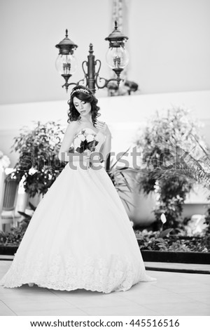 Portrait of charming red-haired bride model with wedding bouquet at hand posed background lantern on great wedding hall indoor. Black and white photo
