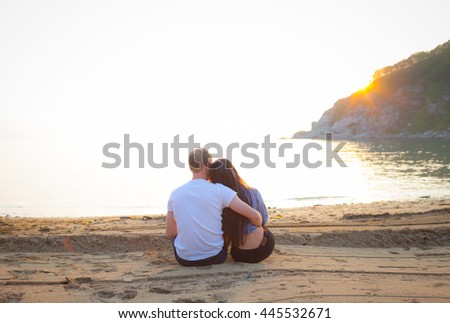 Loving couple sitting on the sandy beach. Romantic couple meets sunset on the ocean. Relations. Happiness.