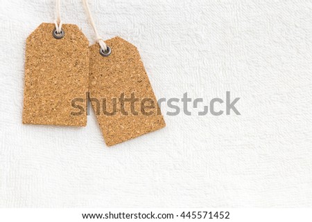 Blank natural cork label tag on white towel texture.