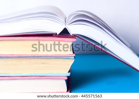 Open book, stack of colorful hardback books on light table. Back to school.. Toned image.
