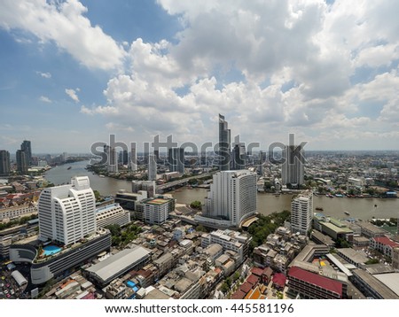 Cityscape and modern building near the river in the afternoon at Chao Phraya River in Bangkok, Thailand under blue sky and cloud
