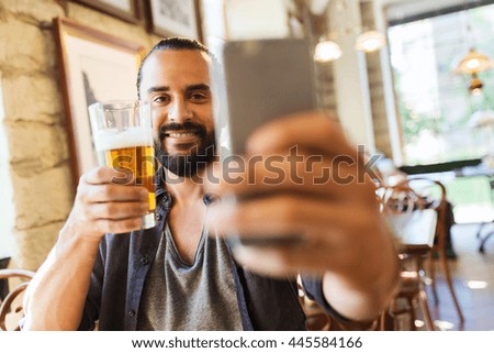 people and technology concept - man with smartphone drinking beer and taking selfie at bar or pub
