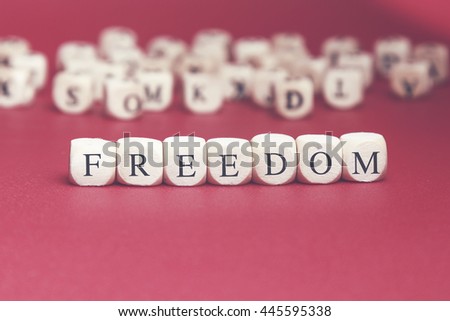 Freedom word written on wood cube with red background