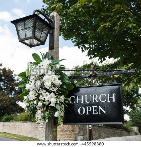 UK Church open sign, with flowers and lamp on oak pole.