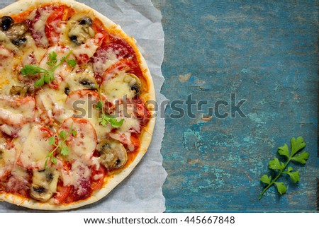 Tasty Italian pizza with tomatoes, cheese and mushrooms served vintage wooden table background.