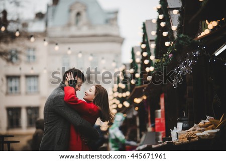 Happy couples on the city square decorated for a Christmas market Royalty-Free Stock Photo #445671961