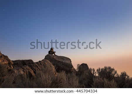 Sunset at the top of Antelope Island with silhouette of female sitting on rocks near Salt Lake City, Utah. 