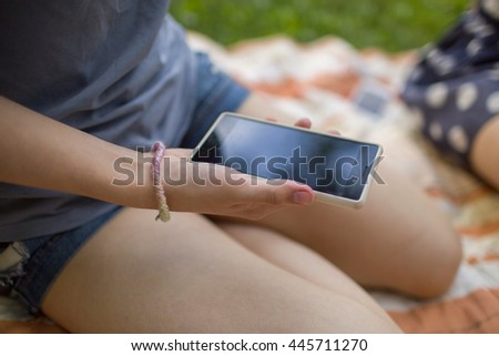 woman sitting outdoors and holding a smart phone