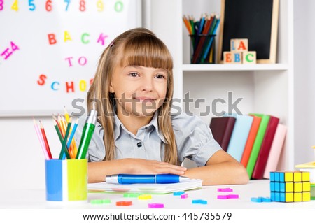 Portrait of a adorable little girl in school at the desk