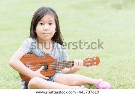 cute asian girl play Ukulele in park or green field