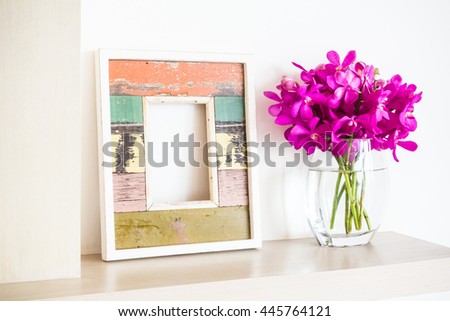 Old wooden photo frame with orchid flower in vase decoration interior of room