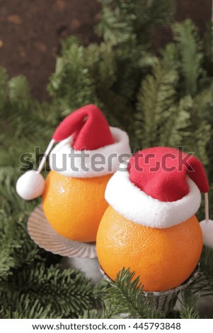 Oranges in red Christmas caps on a background of green branches Christmas trees, festive decorations
