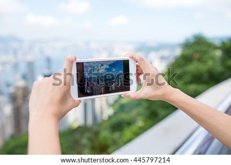 Woman using cellphone to take photo of Hong Kong city
