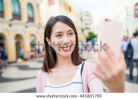 Woman using mobile phone to take selfie in Senado Square of Macau city