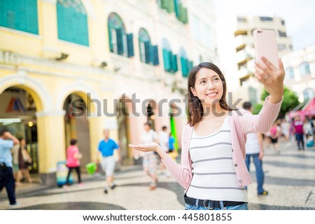 Young woman taking photo by cellphone in Macau