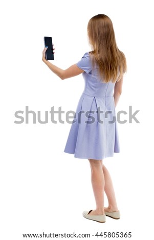 back view of standing young beautiful  girl with tablet computer in the hands of. girl  watching. Rear people collection.  backside of person.  Isolated over white background. 