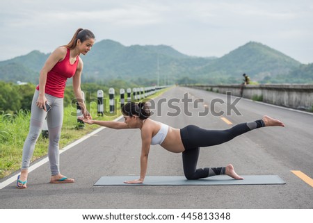 Young healthy pregnant woman doing Yoga exercise on beautiful mountain and road background