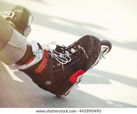 Professional rollerblader wearing aggressive inline skates sitting on concrete ramp in outdoor skate park.Extreme sports athlete wear roller blades for tricks,grinds.Skater in aggressive rollerblades