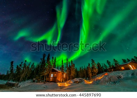 Aurora borealis flying over the chalet in Yellowknife  Royalty-Free Stock Photo #445897690