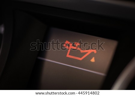Detail of the dashboard of a car, with the oil alert icon lit up.