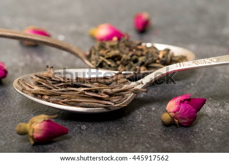 silver spoons full of green and oolong blue tea with rose buds 