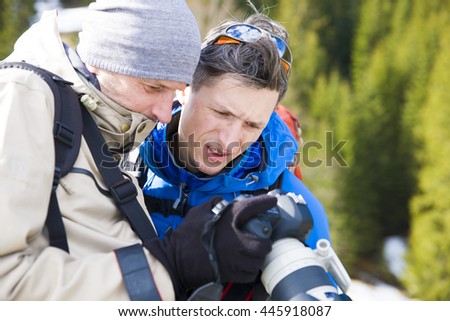 The photographer shows the photos to a friend after traveling through the winter mountains.
