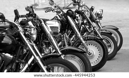 Black and white photography of group motorbikes parked together on outdoors background.