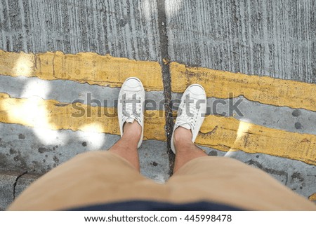 Top view of a man standing on the road with the yellow road marking lines.
