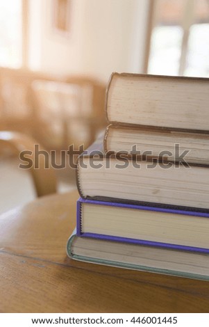 old book stack on wooden table with blur library background