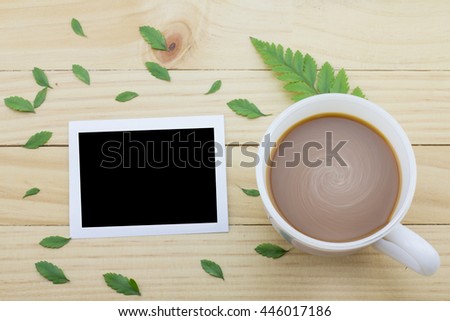 Coffee mug with green foot fern and notes on yellow rustic table. flower petals