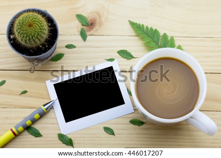 Coffee mug with green foot fern, Flower petals, Cactus flower, Pen and notes on yellow rustic table.