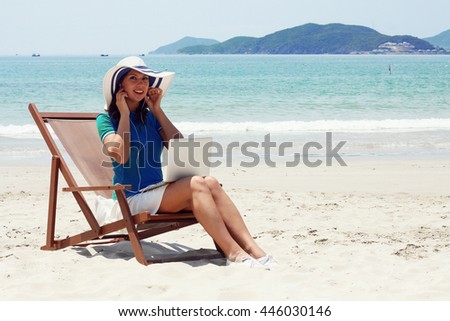 Beautiful  woman with a bag working on laptop computer at beach