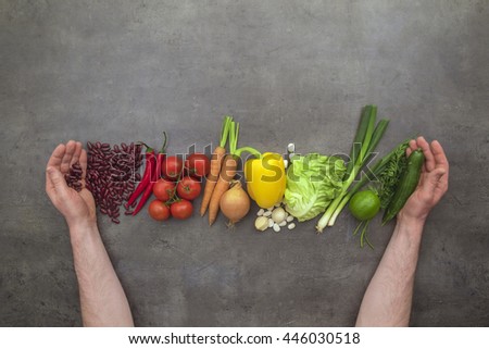 Hands harvesting fresh vegetables. Top view on man hands, vegetables on grey kitchen table. Flat lay food concept.