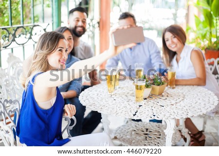 Five young good looking Latin friends taking a selfie with a smartphone during a barbecue outdoors