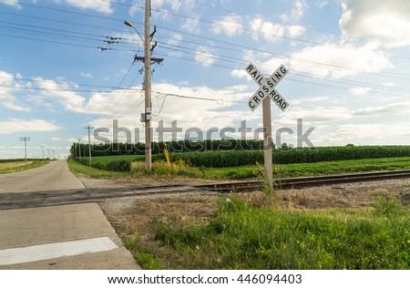 Railroad crossing with rural Midwest landscape in background.