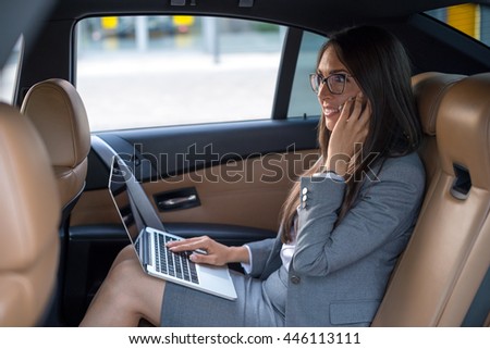 Executive businesswoman in car work on her laptop. 