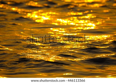 Abstract background blurry image of water in lake with sunrise lighting reflection.