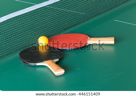 Two table tennis or ping pong rackets and balls on a green table with net Royalty-Free Stock Photo #446151409