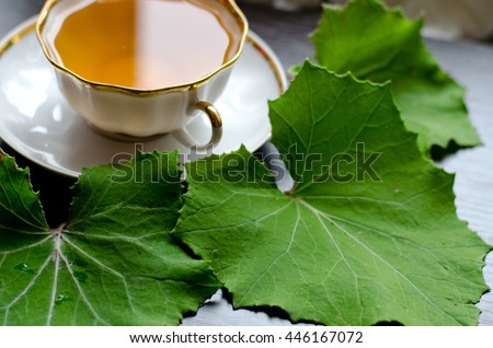 porcelain Cup of coltsfoot tea on a background of dark wood