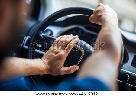 Close up shot of a man's hands holding a car's steering wheel and honking the horn. Royalty-Free Stock Photo #446190121