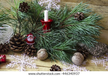Fluffy pine branch with a candle, Santa Claus, pine cones and snowflakes
