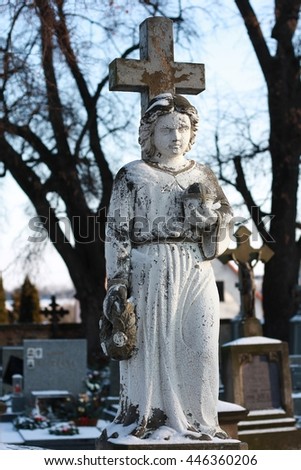 A stone statue of an angel on a winter cemetery