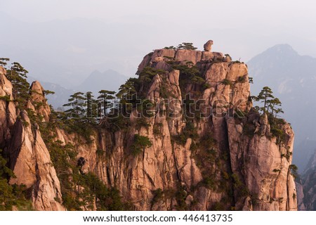 Sunrise from Lion Peak, Huangshan Mountain, China. Early morning sun lights the cliffs below and observation deck at Lion Peak, Yellow Mountains. Mountain range dissolves in the layers of atmosphere.