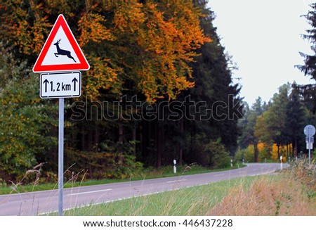 Warning sign when urban road enters forest. Roadsign is in bright colors. Low depth of field with focus on sign.
