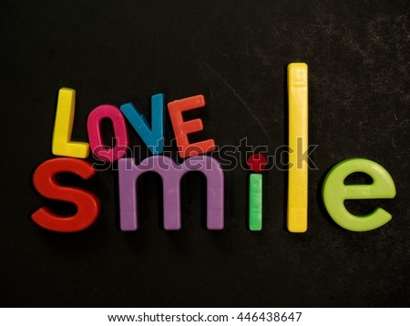 Love and smile! Inspirational message in vibrant colorful magnet letters on black background