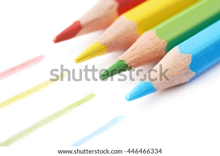 Four colorful drawing pencils composition with the traces of paint, isolated over the white background, close-up crop fragment