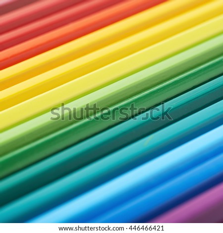 Multiple colorful color pencils composition arranged in a line to form a rainbow gradient, close-up crop fragment