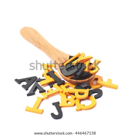 Pile of black and orange painted wooden letters with the wooden serving spoon over it, composition isolated over the white background